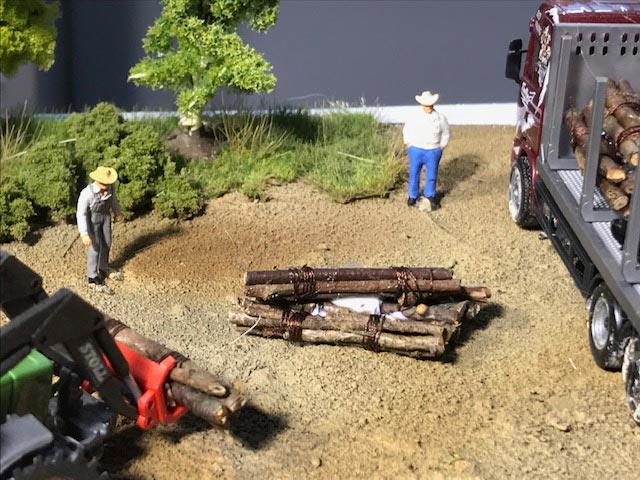 Detailaufnahme Totholzbündel neben Miniatur Traktor und LKW